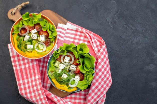 Vista superior sabrosa ensalada de verduras con queso, pepinos y tomates sobre fondo oscuro