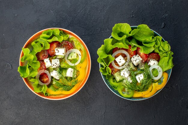 Vista superior sabrosa ensalada de verduras con queso, pepinos y tomates sobre fondo oscuro