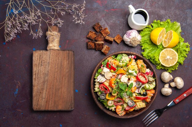 Vista superior de la sabrosa ensalada de verduras con rodajas de limón fresco en el cuadro negro