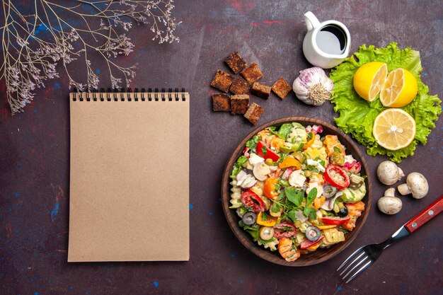 Vista superior de la sabrosa ensalada de verduras con rodajas de limón fresco en negro