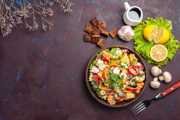 Vista superior de la sabrosa ensalada de verduras con rodajas de limón fresco en la oscuridad