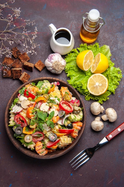 Vista superior de la sabrosa ensalada de verduras con rodajas de limón fresco en la oscuridad