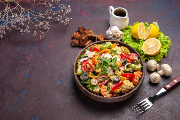 Vista superior de la sabrosa ensalada de verduras con rodajas de limón fresco en la oscuridad