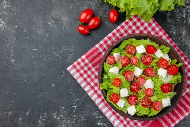 Vista superior sabrosa ensalada de verduras con tomates con queso en rodajas y condimentos sobre fondo oscuro comida color dieta almuerzo salud