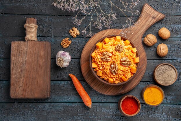 Vista superior sabrosa ensalada de zanahoria con nueces y condimentos en la dieta de alimentos de color azul oscuro ensalada de escritorio tuerca salud