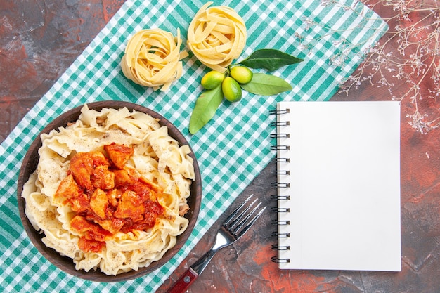 Vista superior sabrosa masa cocida con pollo y salsa en un plato de comida de pasta de superficie oscura