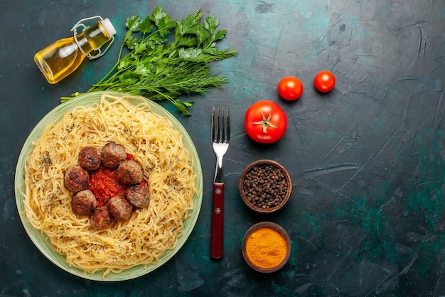 Foto gratuita vista superior sabrosa pasta italiana con albóndigas y diferentes condimentos en el escritorio azul oscuro