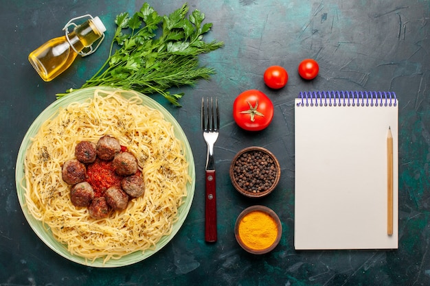 Vista superior sabrosa pasta italiana con albóndigas y diferentes condimentos sobre el fondo azul oscuro