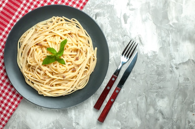 Vista superior de la sabrosa pasta italiana con cubiertos sobre fondo blanco.