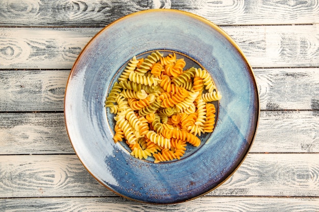 Vista superior sabrosa pasta italiana pasta espiral cocida inusual en madera gris