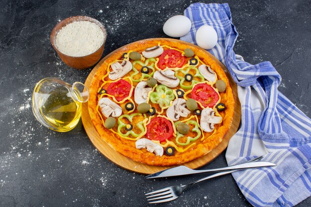 Vista superior sabrosa pizza de champiñones con tomates rojos, pimiento, aceitunas y champiñones, todos en rodajas por dentro con huevos en la pizza de comida de escritorio oscuro