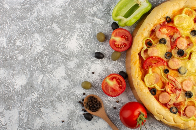 Vista superior sabrosa pizza con queso con aceitunas salchichas y tomates rojos sobre fondo gris comida de masa italiana de comida rápida