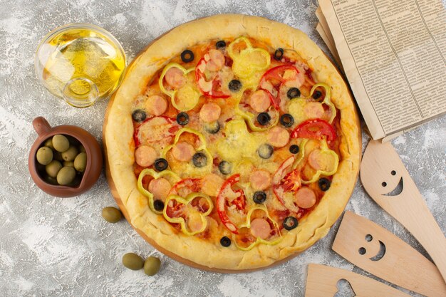 Vista superior sabrosa pizza con queso con salchichas de aceitunas negras y tomates rojos junto con aceite y aceitunas en el escritorio gris horneado de masa italiana