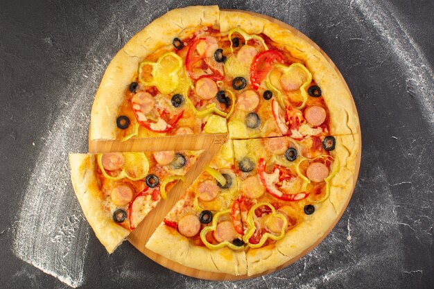 Vista superior sabrosa pizza con queso con tomates rojos, aceitunas negras, pimientos y salchichas sobre el fondo oscuro, comida rápida, masa italiana