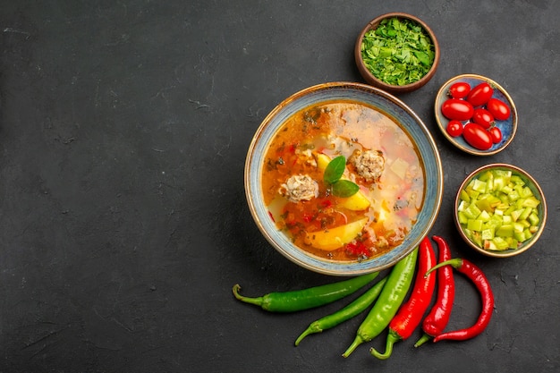 Vista superior sabrosa sopa de albóndigas con verduras y pimienta en el color del plato de salsa de mesa oscura