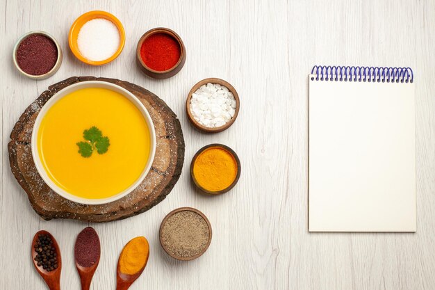 Vista superior de la sabrosa sopa de calabaza con diferentes condimentos en blanco