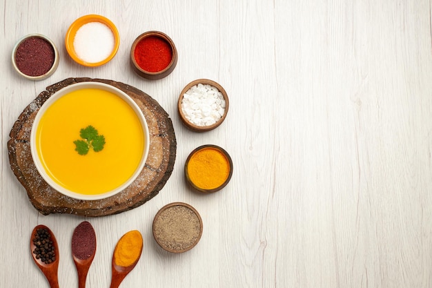 Vista superior de la sabrosa sopa de calabaza con diferentes condimentos en blanco