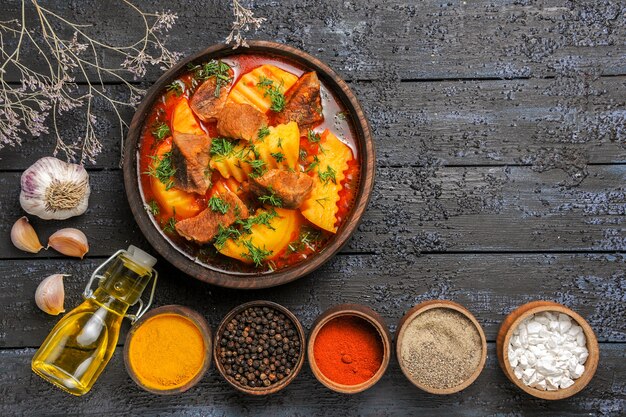 Vista superior sabrosa sopa de carne con patatas y condimentos en el escritorio oscuro