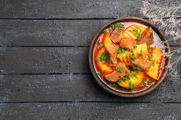 Vista superior sabrosa sopa de carne con verduras y patatas en el escritorio oscuro