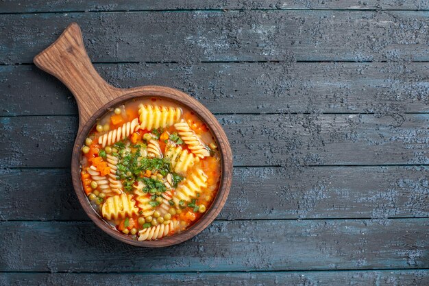 Vista superior de la sabrosa sopa de pasta de pasta italiana en espiral con verduras en la sopa de escritorio de color azul oscuro plato de cocina vegetal color pasta italiana