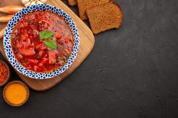 Vista superior sabrosa sopa de remolacha ucraniana borsch con panes de pan oscuro en el espacio oscuro