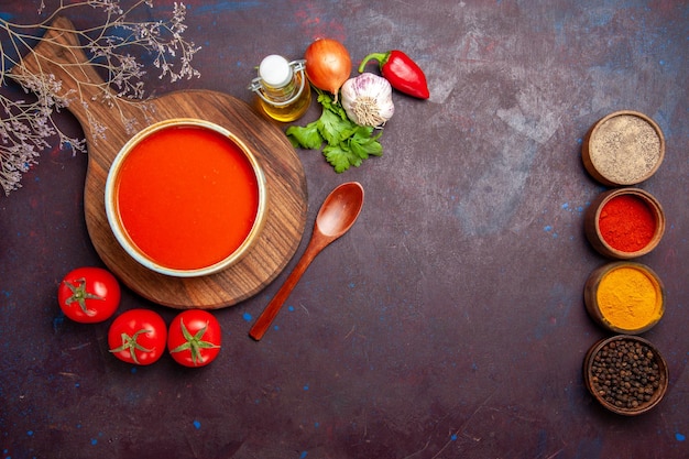 Vista superior de la sabrosa sopa de tomate con condimentos y tomates frescos en la oscuridad