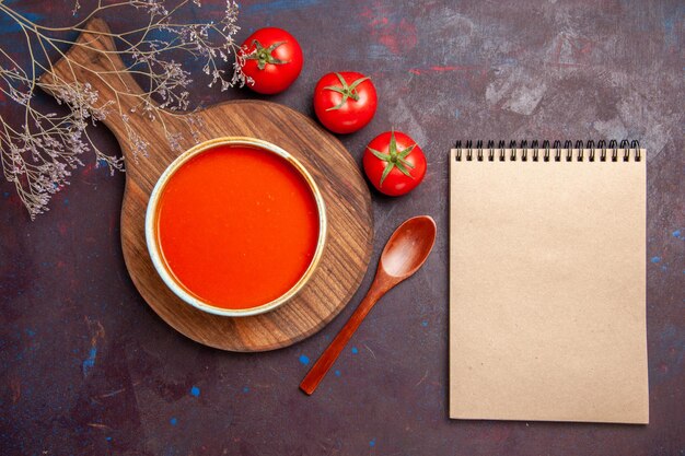 Vista superior de la sabrosa sopa de tomate con tomates frescos en la oscuridad