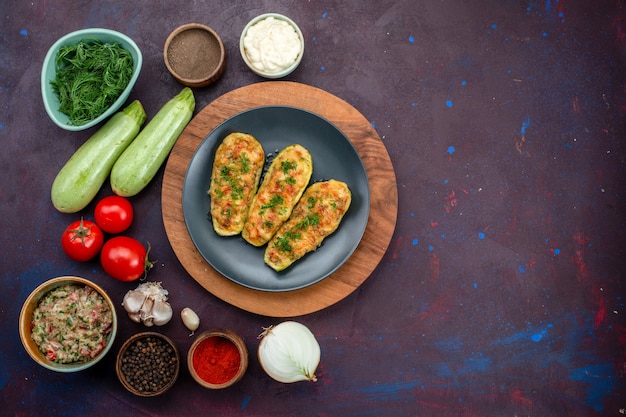 Vista superior de sabrosas calabazas al horno con verduras junto con condimentos de verduras frescas en una superficie oscura