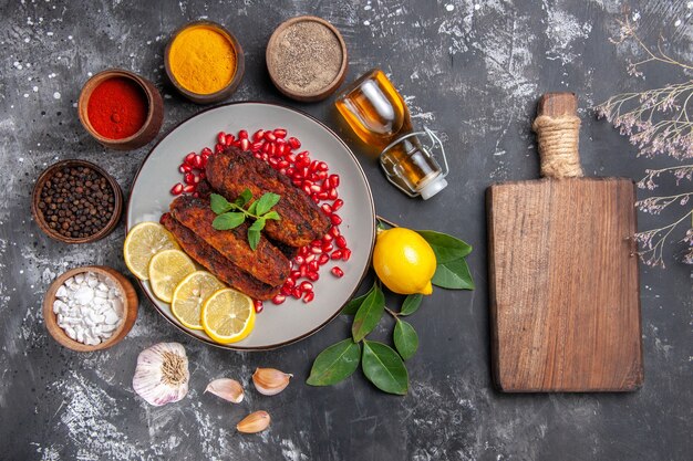 Vista superior sabrosas chuletas de carne con condimentos en la comida de la foto del plato de fondo gris