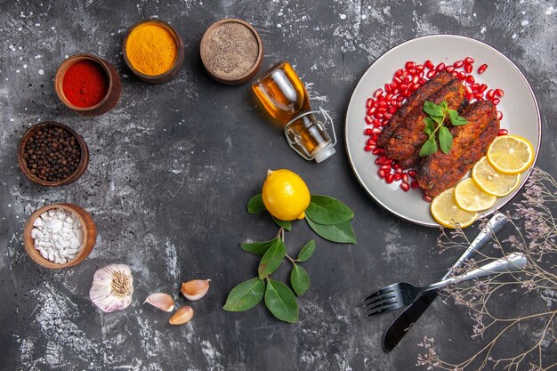 Vista superior sabrosas chuletas de carne con condimentos en la comida de la foto del plato de fondo gris