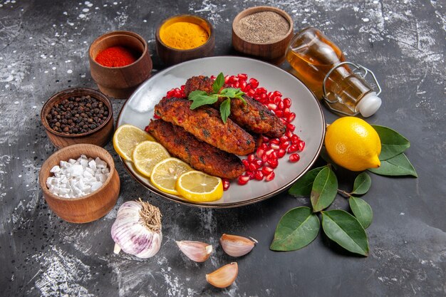 Vista superior sabrosas chuletas de carne con condimentos en un plato de comida de escritorio gris