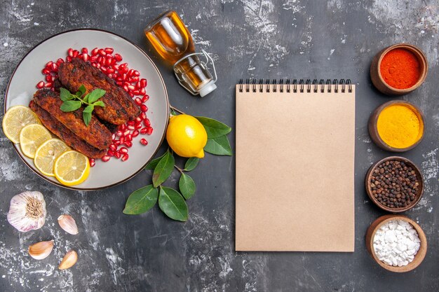 Vista superior sabrosas chuletas de carne con condimentos en el plato de comida de fondo gris