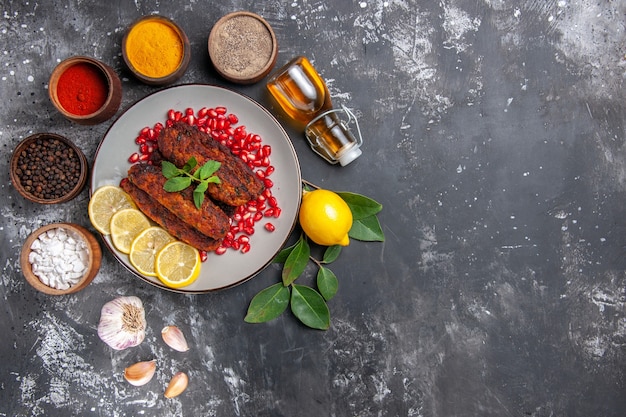 Vista superior sabrosas chuletas de carne con condimentos en el plato de comida de fondo gris