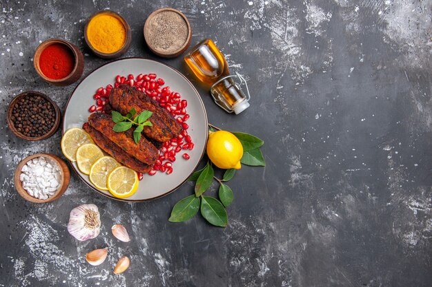 Vista superior sabrosas chuletas de carne con condimentos en el plato de comida de fondo gris