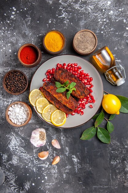 Vista superior sabrosas chuletas de carne con condimentos en plato de comida de piso gris