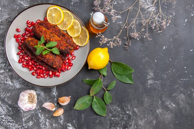 Vista superior sabrosas chuletas de carne con rodajas de limón en el fondo gris plato foto comida