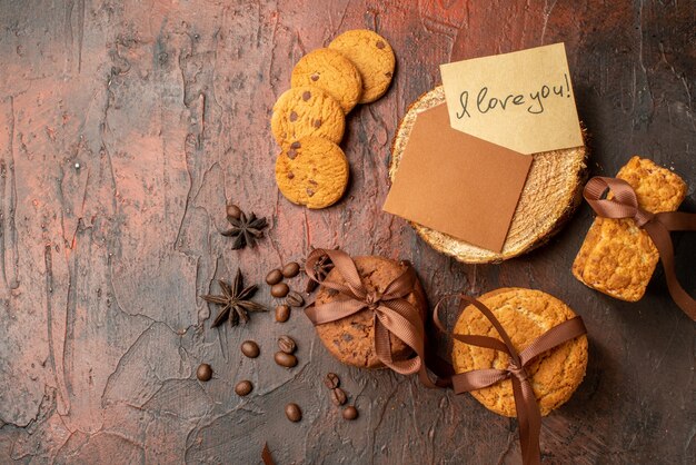 Vista superior sabrosas galletas atadas con cuerda, galletas, anís, carta de amor en la mesa de color rojo oscuro con