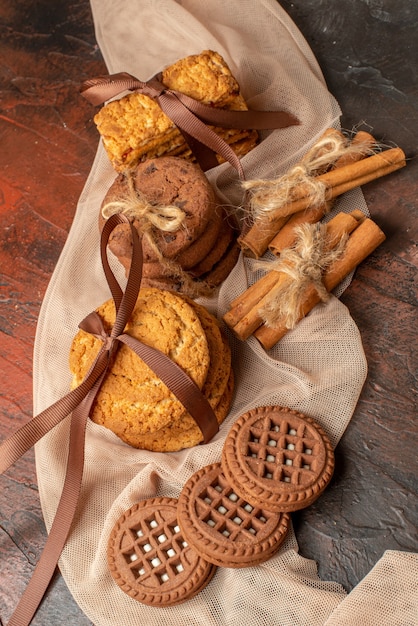 Vista superior sabrosas galletas atadas con cuerda palitos de canela galletas con crema en la mesa oscura