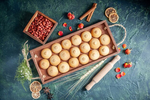 Vista superior sabrosas galletas dentro de una caja de madera sobre fondo oscuro pastel de galletas de galleta de azúcar color nueces dulces tortas de té