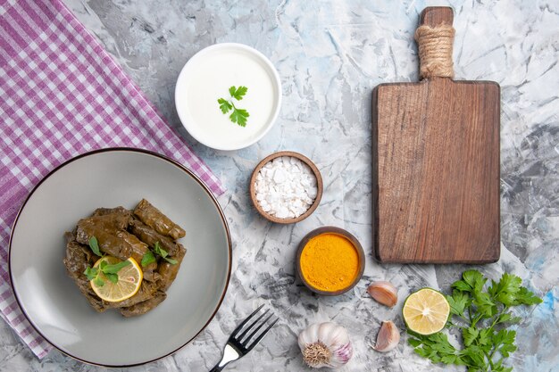 Vista superior de las sabrosas hojas de dolma con condimentos sobre fondo blanco