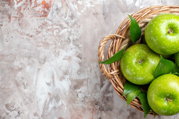 Vista superior sabrosas manzanas verdes dentro de la cesta sobre el fondo claro