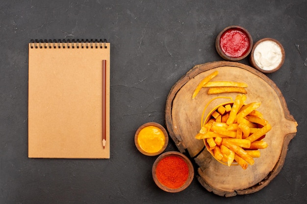 Foto gratuita vista superior de sabrosas papas fritas con salsas en mesa negra