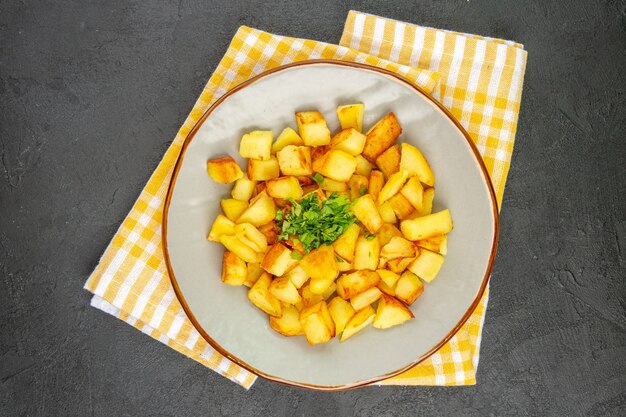 Vista superior de sabrosas patatas fritas dentro de la placa sobre la superficie gris oscuro