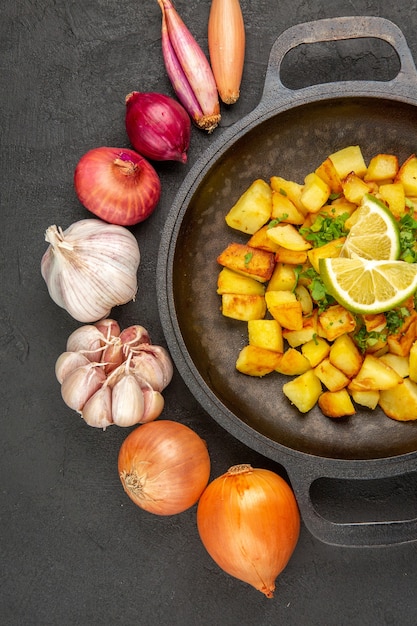 Foto gratuita vista superior de sabrosas patatas fritas dentro de la sartén con limón y ajos en la superficie oscura