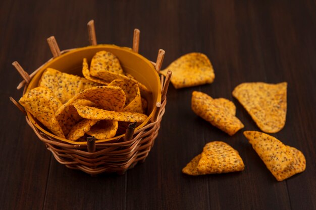 Vista superior de sabrosas patatas fritas picantes en un cubo con patatas fritas aislado en una mesa de madera