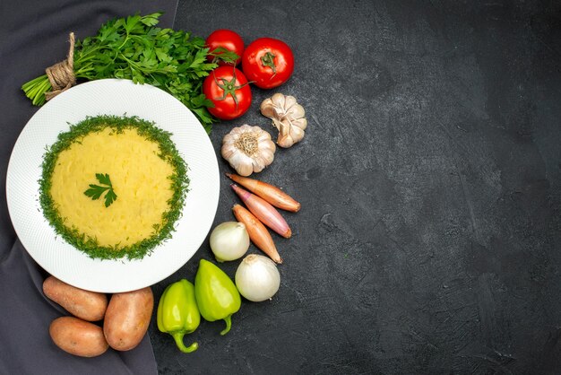 Vista superior de sabrosas patatas trituradas con verduras y verduras frescas en negro