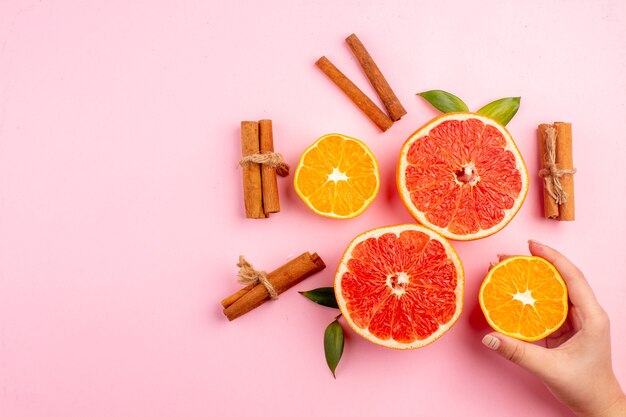 Vista superior de sabrosas rodajas de fruta de pomelos con canela en la superficie rosa