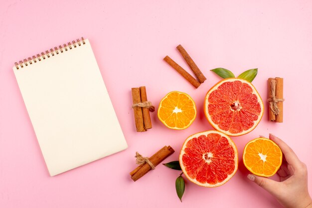 Vista superior de sabrosas rodajas de fruta de pomelos con canela en la superficie rosa