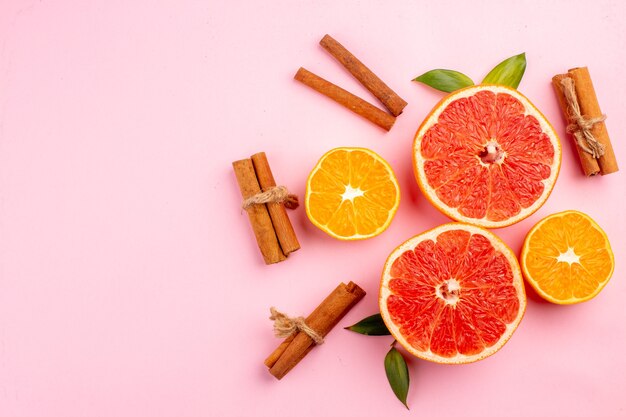 Vista superior de sabrosas rodajas de fruta de pomelos con canela en la superficie rosa