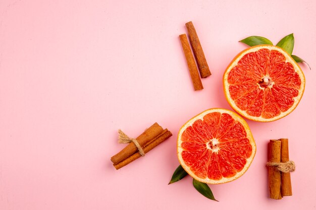 Vista superior de sabrosas rodajas de fruta de pomelos en la superficie rosa